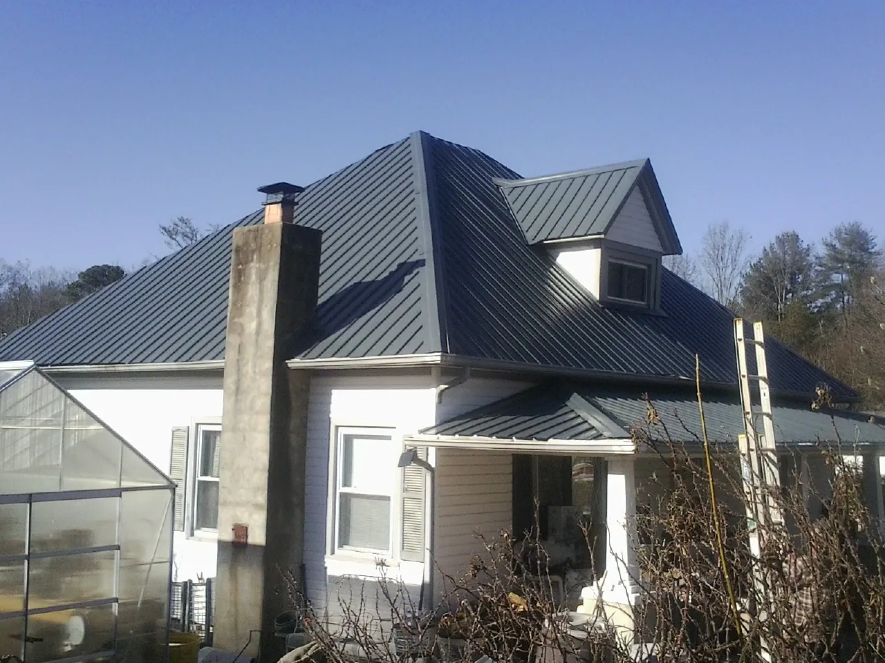 Dark blue standing seam metal roof on a white farmhouse with dormer — Slate & Tile Roof Repair by Roofing Brothers in Prairie Du Sac