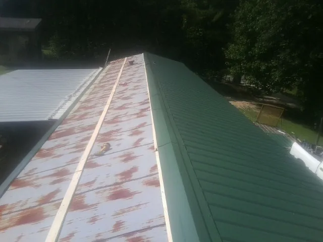 Old rusted panels beside newly installed green metal roofing — Wind Damage Roof Repair by Roofing Brothers in Prairie Du Sac