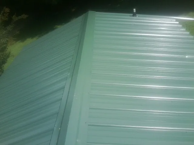 New green metal panels meeting at the ridge of a roof — Flat Roof Repair work by our crew in Prairie Du Sac