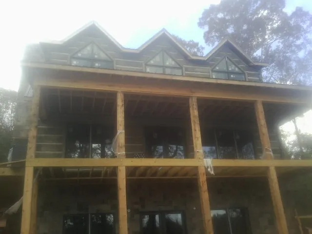 Dormers and porch framing on a large log home under construction — Roof Coating work by our crew in Prairie Du Sac
