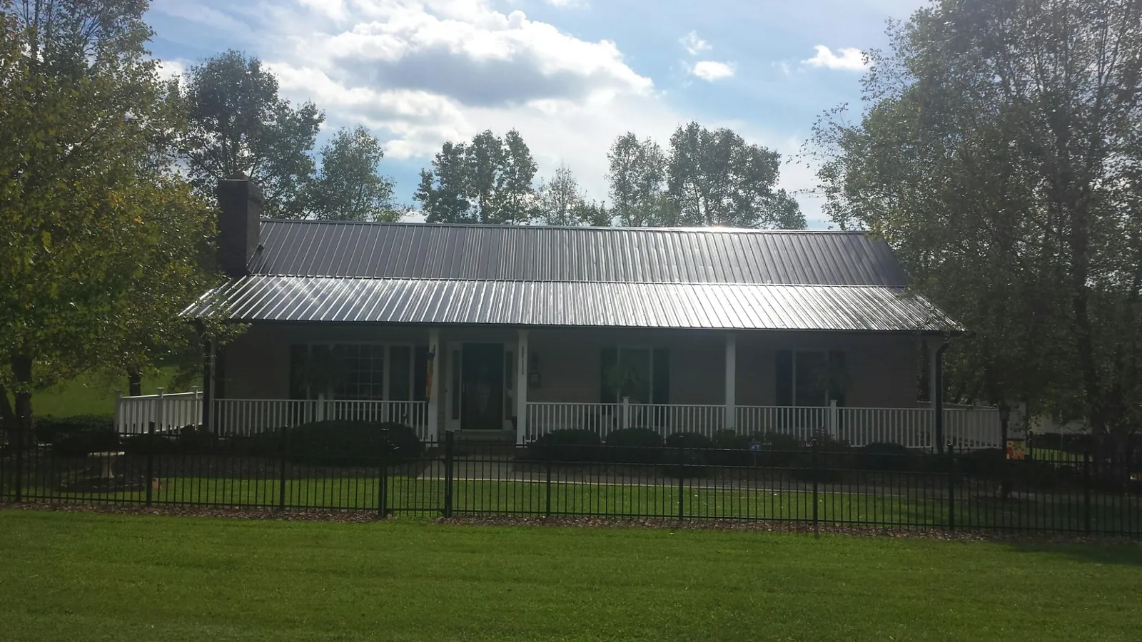 Gray metal roof on a brick ranch with a full width front porch — Gutter Guard Installation work by our crew in Prairie Du Sac