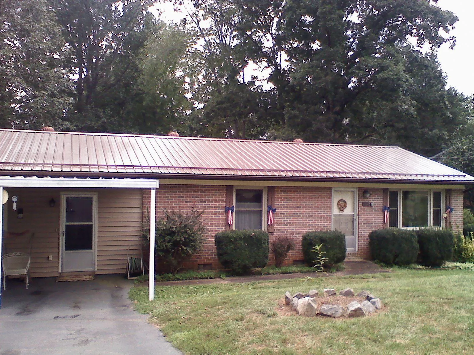 Bronze metal roof and carport on a brick ranch home — Roof Repair work by our crew in Prairie Du Sac