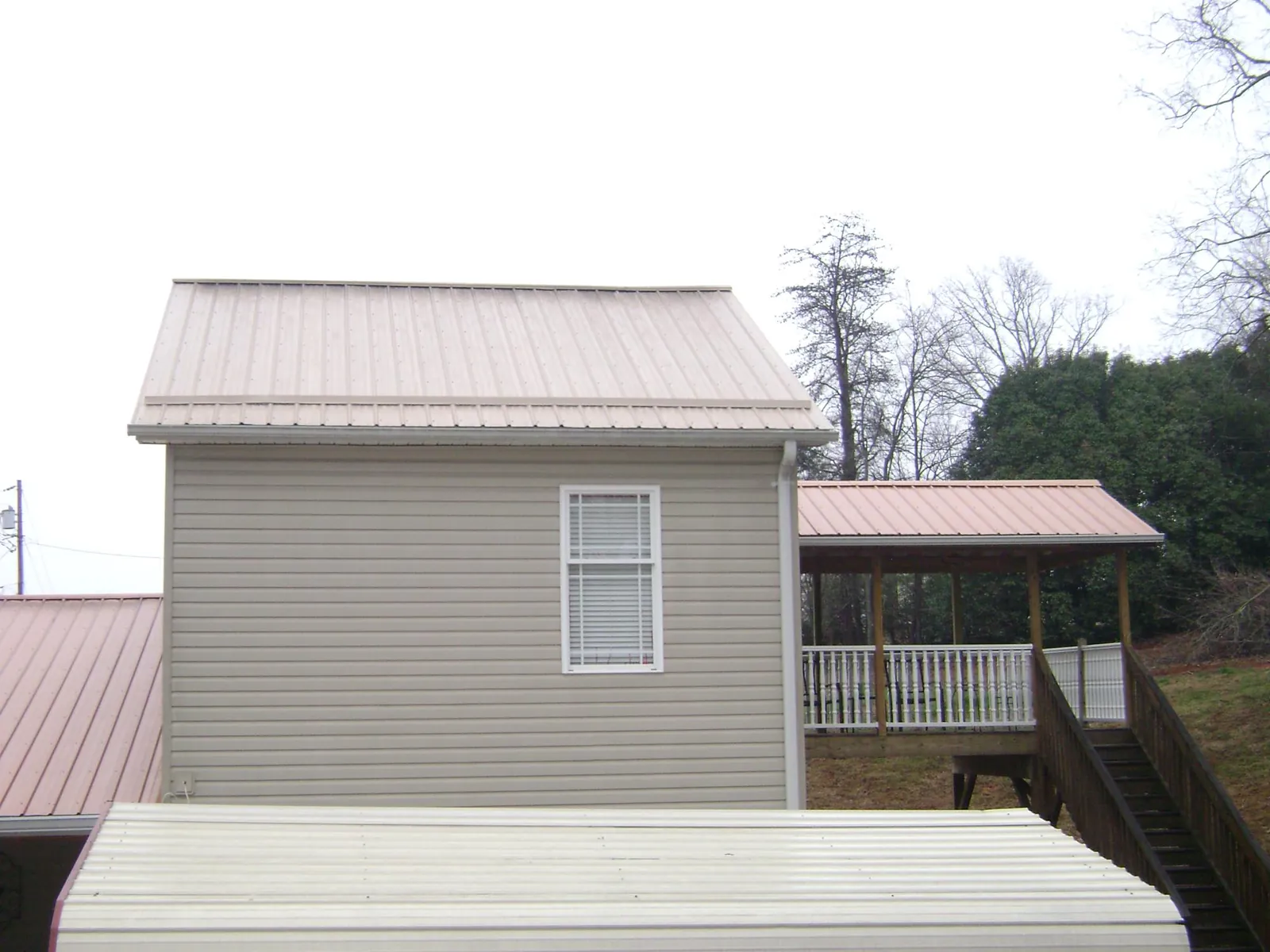 Tan metal roofs on a two story addition and attached porch, from a Roof Replacement job in Prairie Du Sac