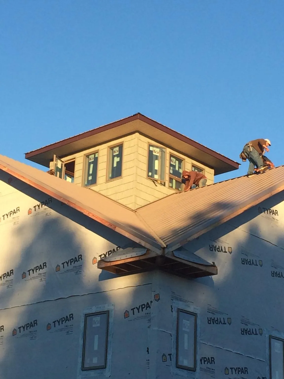 Roofers working around a rooftop cupola on a new metal roof at sunset — Roof Waterproofing in Prairie Du Sac by Roofing Brothers